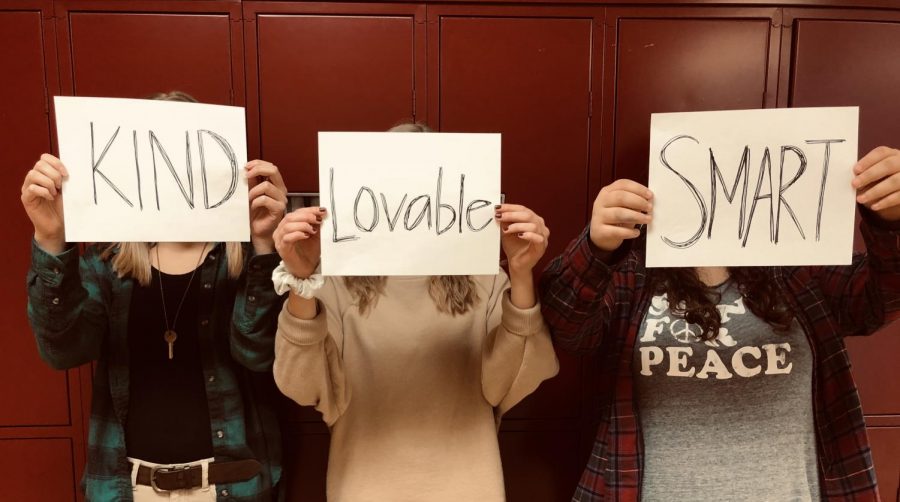 Students hold pieces of paper that have positive words that represent who they are. 