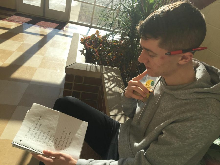 Senior Jacob Butzin examines his grocery list while enjoying coffee.