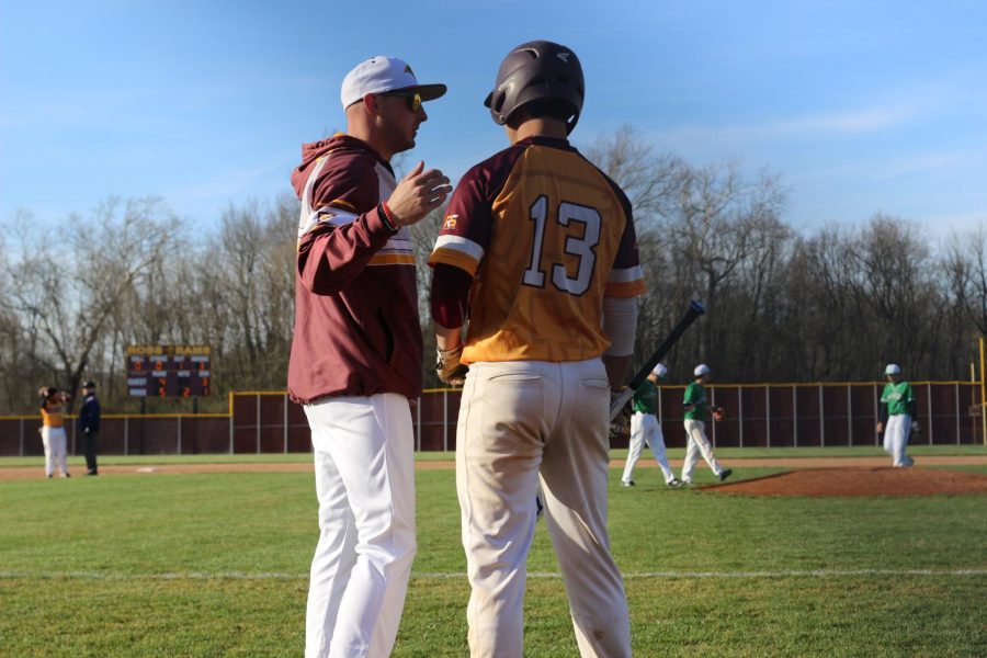 Coach Ben Toerner gives junior Ethan Hall advice before his upcoming at-bat after a Harrison pitching change. 