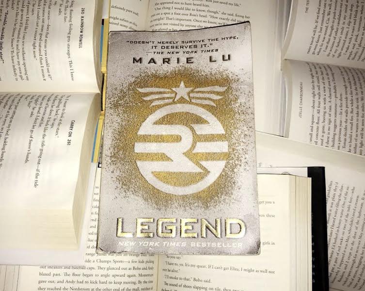 Legend by Marie Lu sits at the top of a pile of unique books.