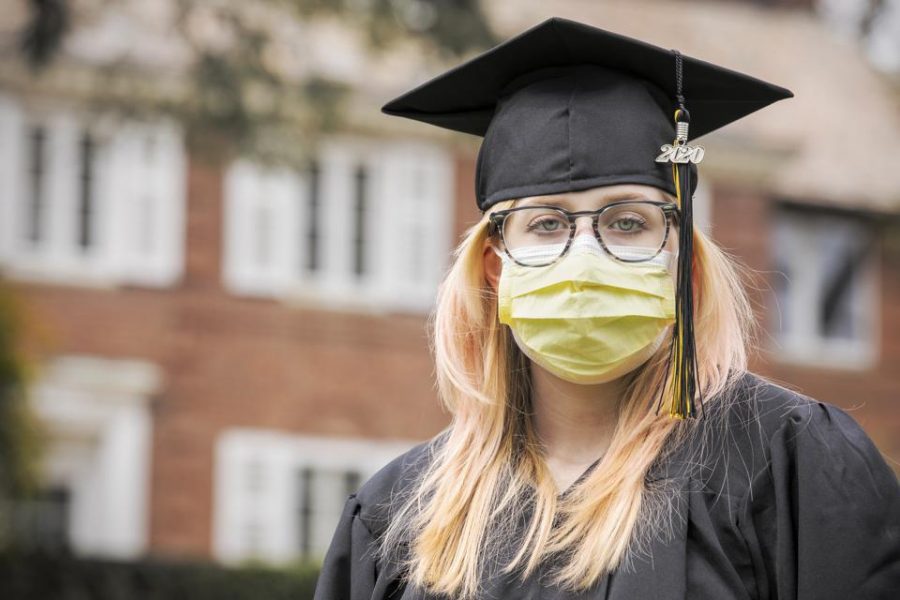 An+unknown+senior+shows+off+her+cap%2C+gown%2C+and+masks+during+her+graduation.+