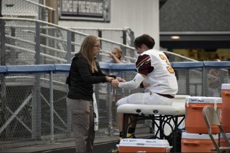 Senior Dylan Hammons is assessed by athletic trainer Kendall Cramer during the varsity Valley View football game.  