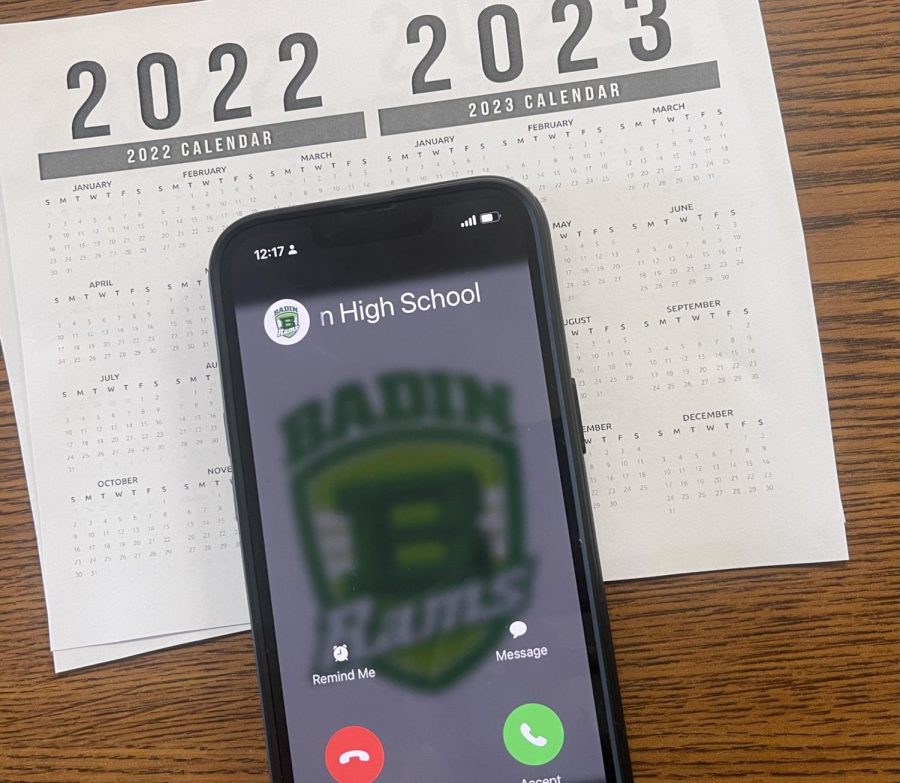 Persons iPhone sits on top of a 2022-2023 monthly calendar, as Badin High school attempts to contact them with the choice to accept or decline the call.