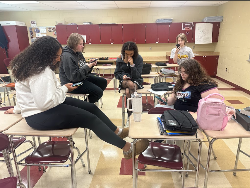 Freshman Briana Frazier, Ruby Harris, Olivia Brown, Quinn Laurens, and Bradley Pharr scrolling through social media.