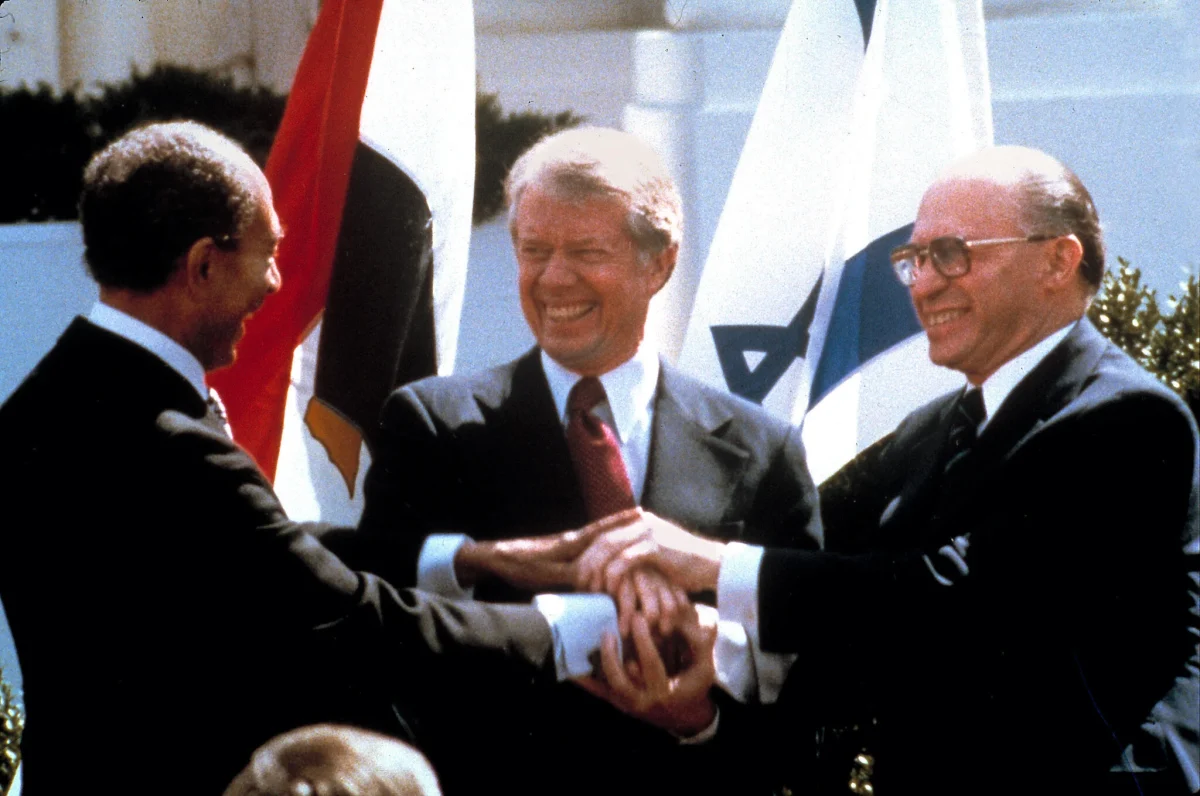 President Carter shakes hands with Egyptian President Anwar Sadat and Israeli Prime Minister Menachem Begin to celebrate the Camp David Accords.